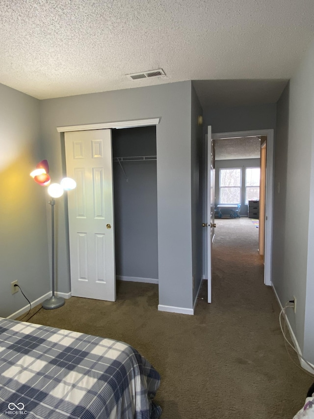 unfurnished bedroom featuring dark colored carpet, a textured ceiling, and a closet