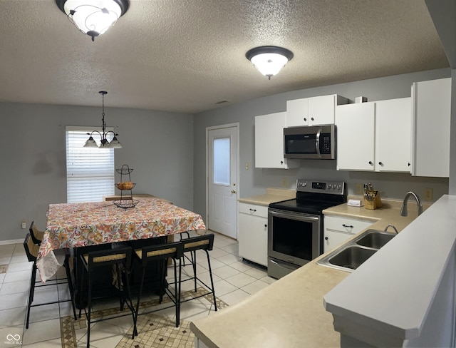 kitchen featuring white cabinets, hanging light fixtures, light tile patterned floors, a textured ceiling, and stainless steel appliances