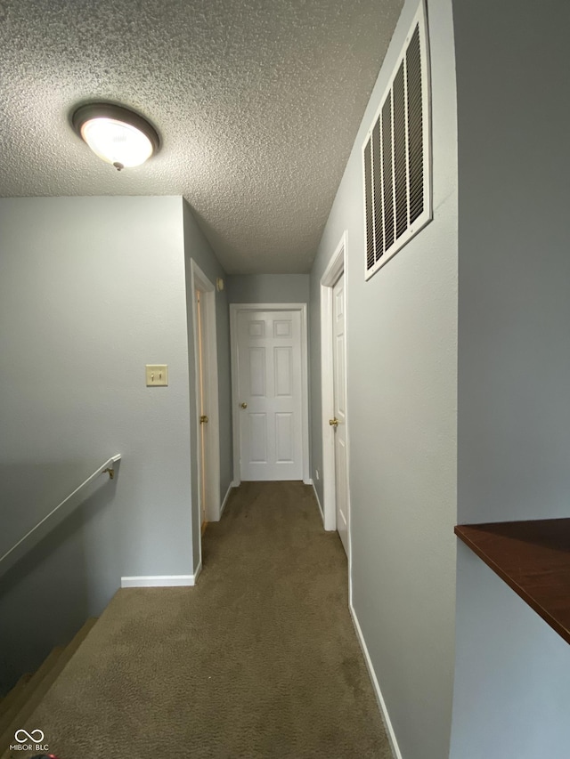 corridor with carpet and a textured ceiling