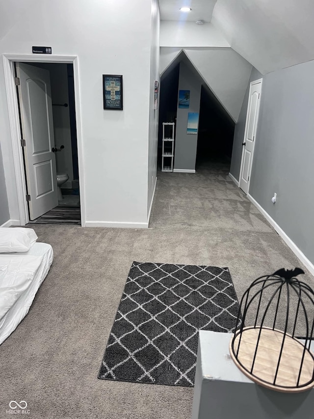 corridor with carpet floors and vaulted ceiling