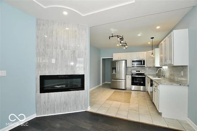 kitchen featuring backsplash, stainless steel appliances, sink, decorative light fixtures, and white cabinets