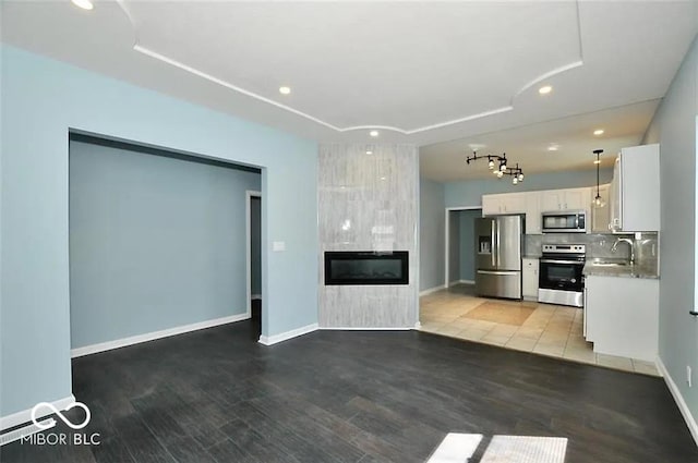 unfurnished living room with a tiled fireplace, sink, and wood-type flooring