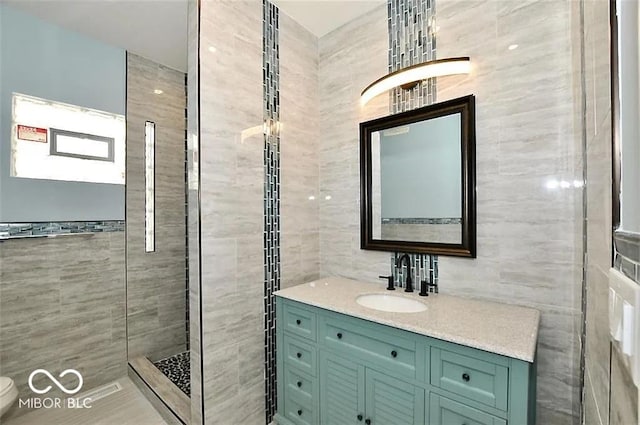 bathroom featuring walk in shower, vanity, and tile walls