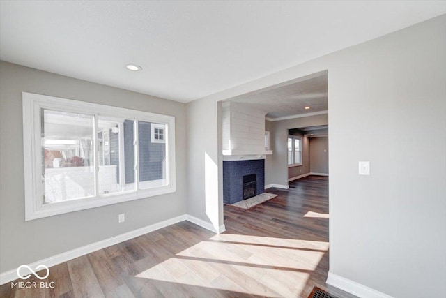 unfurnished living room featuring a fireplace with flush hearth, baseboards, wood finished floors, and recessed lighting