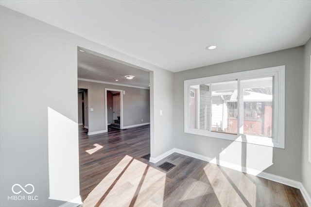 empty room with recessed lighting, dark wood-type flooring, visible vents, baseboards, and ornamental molding