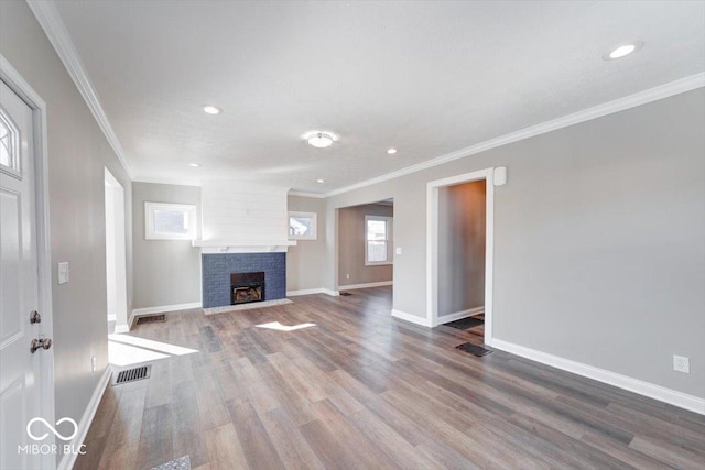 unfurnished living room featuring a fireplace, wood finished floors, visible vents, baseboards, and ornamental molding