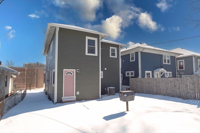 snow covered rear of property with central AC unit and fence