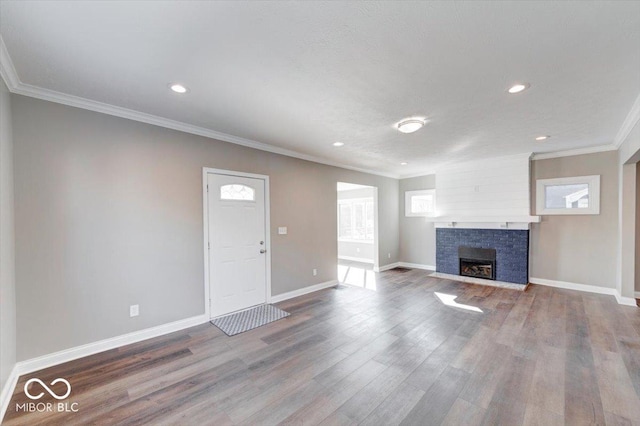 unfurnished living room with a fireplace, crown molding, baseboards, and wood finished floors