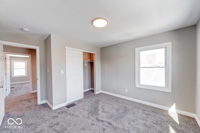 unfurnished bedroom with a closet, carpet flooring, visible vents, and baseboards