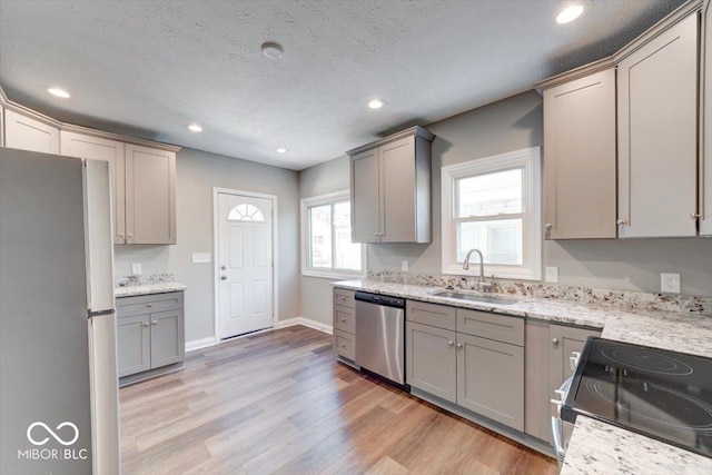 kitchen featuring light wood-style flooring, gray cabinets, stainless steel appliances, a sink, and recessed lighting