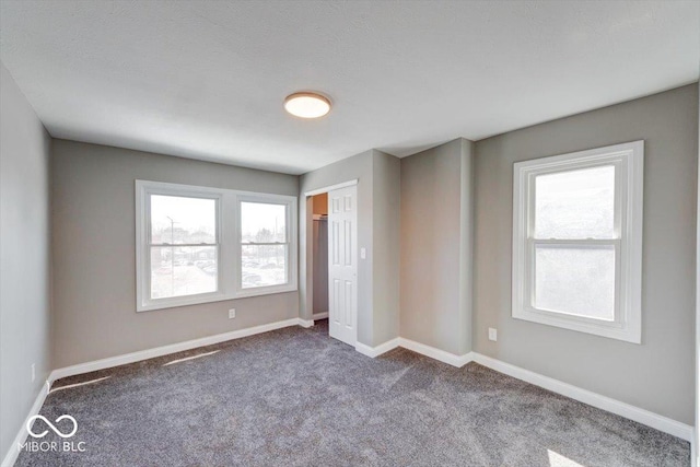 unfurnished bedroom featuring a closet, multiple windows, baseboards, and carpet flooring