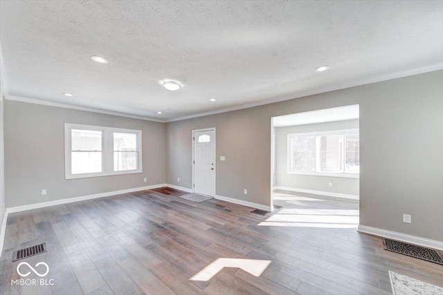 foyer with plenty of natural light, visible vents, dark wood-type flooring, and ornamental molding