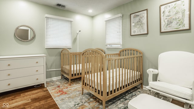 bedroom featuring hardwood / wood-style flooring and a crib