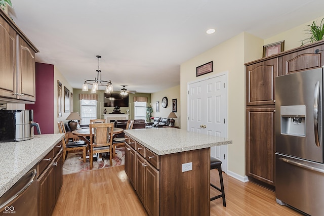 kitchen with ceiling fan, hanging light fixtures, stainless steel appliances, light hardwood / wood-style flooring, and a kitchen island