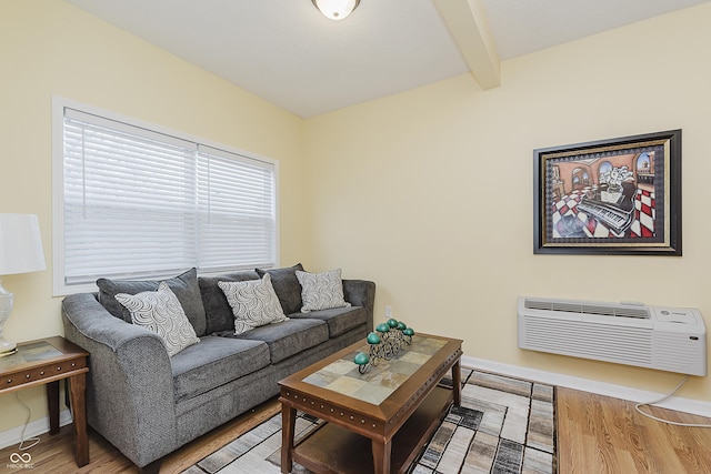 living room featuring beam ceiling, hardwood / wood-style floors, and a wall unit AC