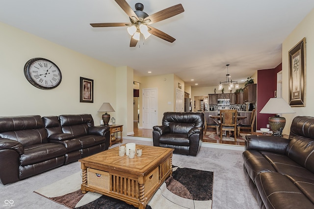 carpeted living room with ceiling fan with notable chandelier