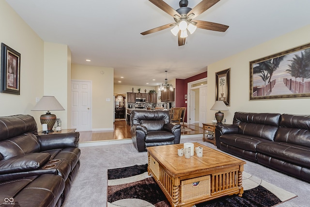 living room featuring light carpet and ceiling fan with notable chandelier