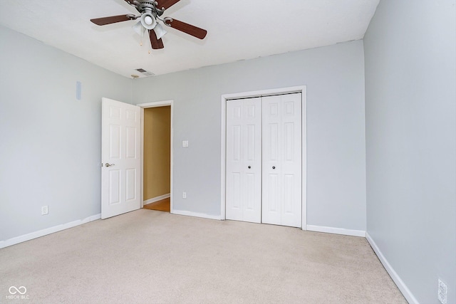 unfurnished bedroom featuring ceiling fan, a closet, and light carpet