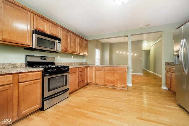 kitchen featuring kitchen peninsula, light hardwood / wood-style flooring, and appliances with stainless steel finishes