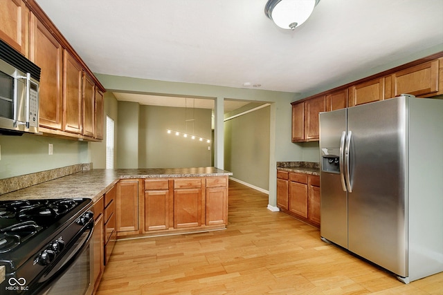 kitchen featuring light wood-type flooring, kitchen peninsula, and stainless steel appliances