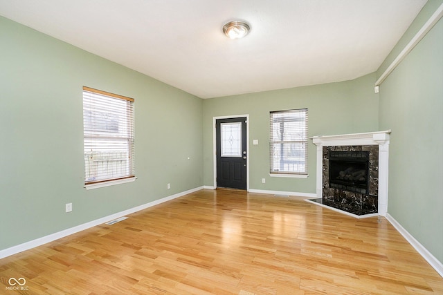 unfurnished living room with light hardwood / wood-style floors and a high end fireplace