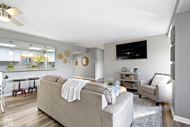 living room with sink, light hardwood / wood-style flooring, and ceiling fan