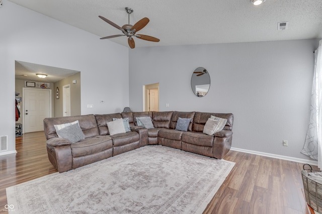 living room featuring vaulted ceiling, ceiling fan, a textured ceiling, and hardwood / wood-style flooring