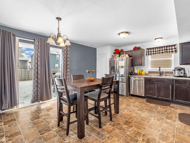 dining room featuring a notable chandelier, sink, and a textured ceiling