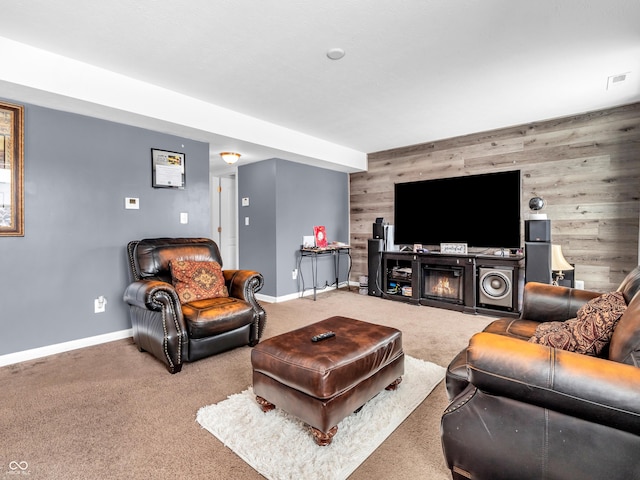 carpeted living room with a fireplace and wooden walls