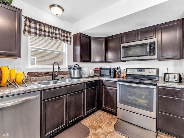 kitchen featuring light tile patterned flooring, dark brown cabinetry, sink, and appliances with stainless steel finishes