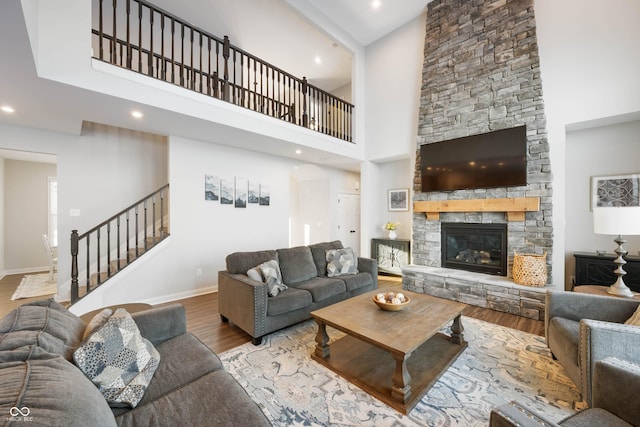 living room featuring a high ceiling, hardwood / wood-style floors, and a stone fireplace