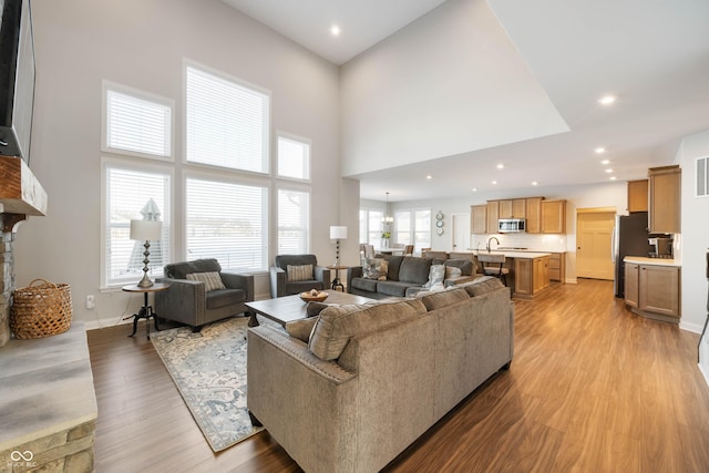 living room featuring a towering ceiling, a wealth of natural light, and light hardwood / wood-style floors