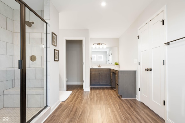 bathroom with toilet, a shower with shower door, hardwood / wood-style flooring, and vanity