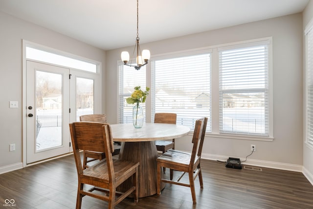 dining room with dark wood-type flooring and an inviting chandelier