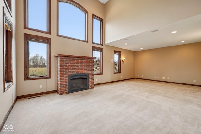 unfurnished living room with a towering ceiling, carpet, a fireplace, and visible vents