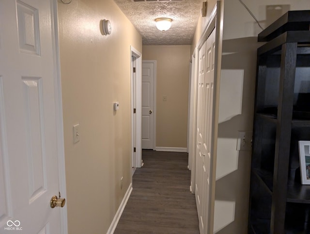 hallway with a textured ceiling and dark wood-type flooring