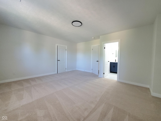 spare room featuring light colored carpet and a textured ceiling