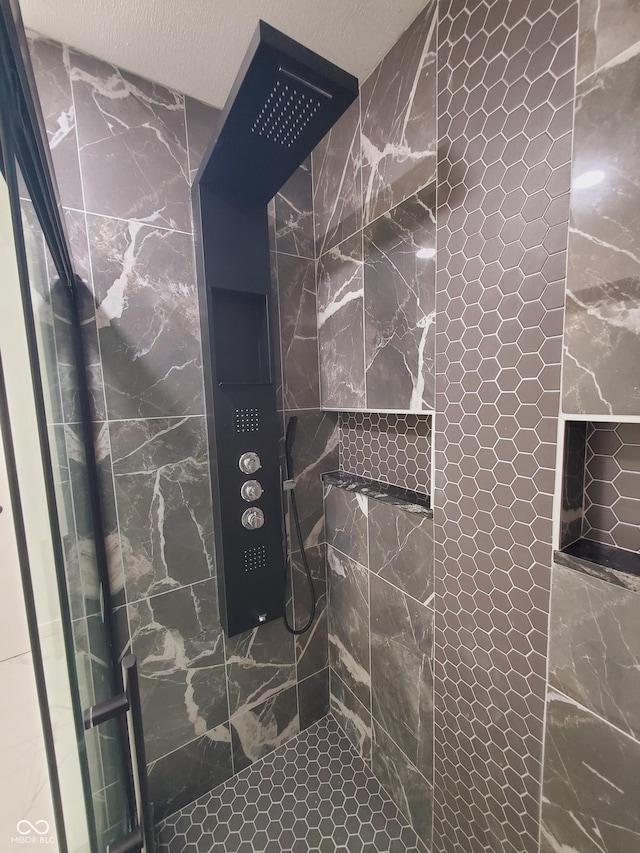 bathroom featuring tiled shower and a textured ceiling