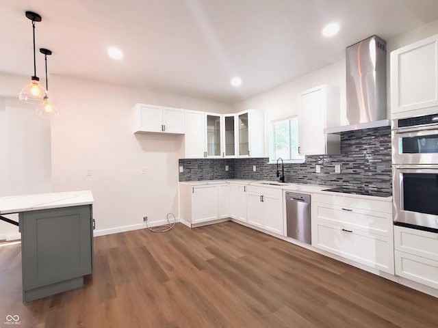 kitchen featuring white cabinetry, wall chimney range hood, hanging light fixtures, and appliances with stainless steel finishes