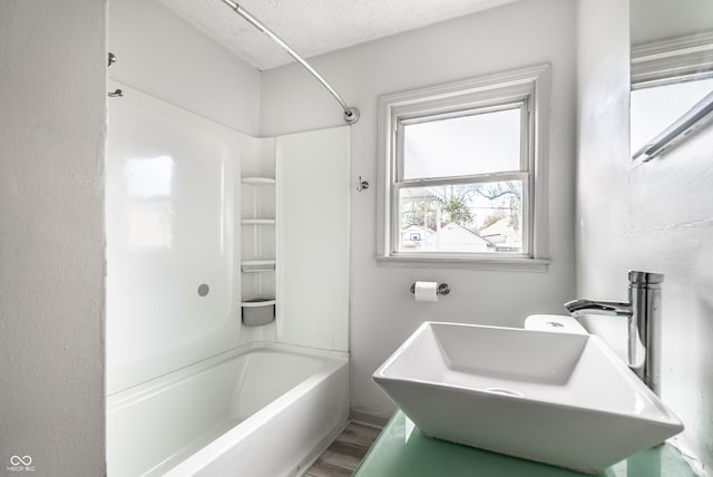 bathroom featuring washtub / shower combination, hardwood / wood-style floors, a textured ceiling, and sink