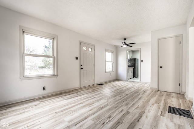 entrance foyer featuring ceiling fan, light hardwood / wood-style flooring, and a textured ceiling