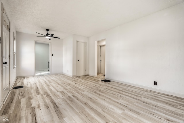 spare room with a textured ceiling, light wood-type flooring, and ceiling fan