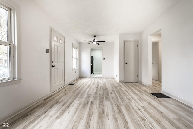 interior space featuring ceiling fan, a textured ceiling, and light hardwood / wood-style flooring