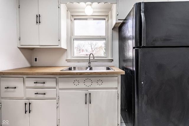 kitchen featuring white cabinetry and black refrigerator