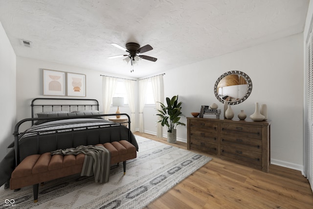 bedroom with ceiling fan, wood-type flooring, and a textured ceiling