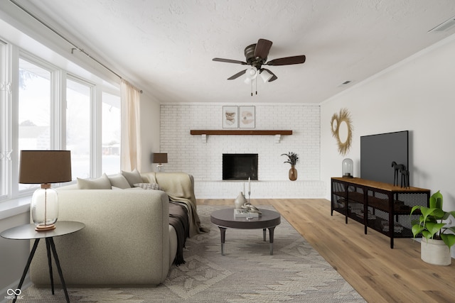 living room with ornamental molding, hardwood / wood-style flooring, ceiling fan, brick wall, and a fireplace