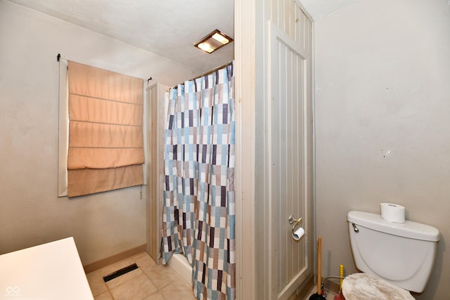 bathroom featuring tile patterned floors, toilet, a textured ceiling, and shower / tub combo with curtain