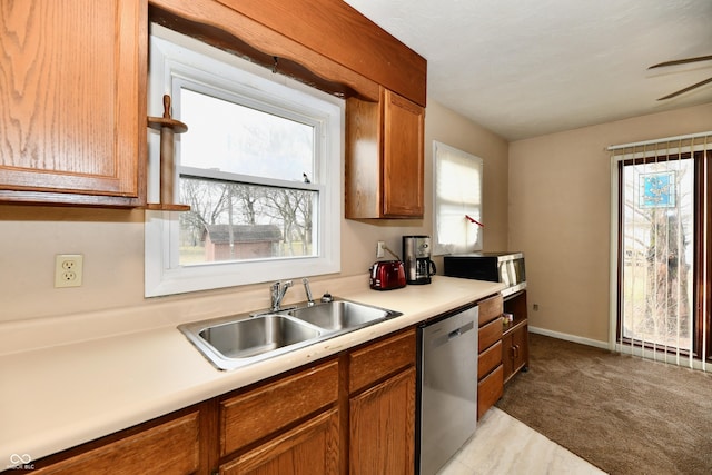 kitchen featuring a healthy amount of sunlight, sink, stainless steel dishwasher, and light carpet