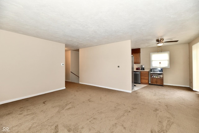 unfurnished living room with ceiling fan, light colored carpet, and a textured ceiling