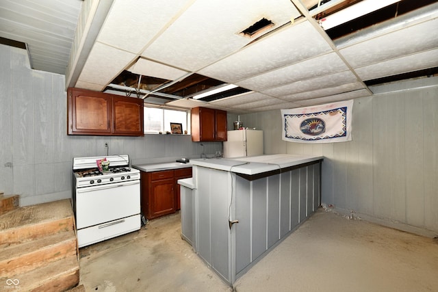 kitchen featuring wood walls, white appliances, and kitchen peninsula